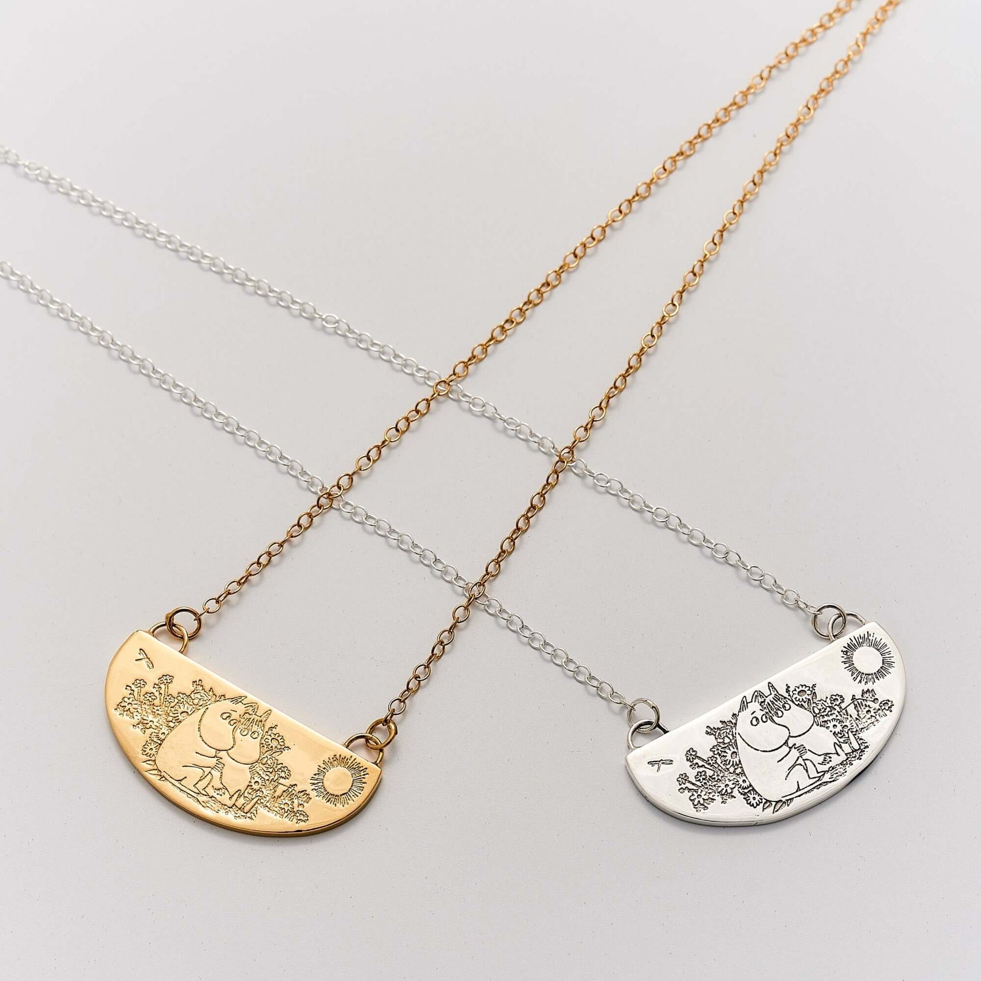 Licensed To Charm flatlay showing Moomin Friends Among Flowers Necklace in 18ct gold vermeil and sterling silver featuring Moomintroll and Snorkmaiden among flowers