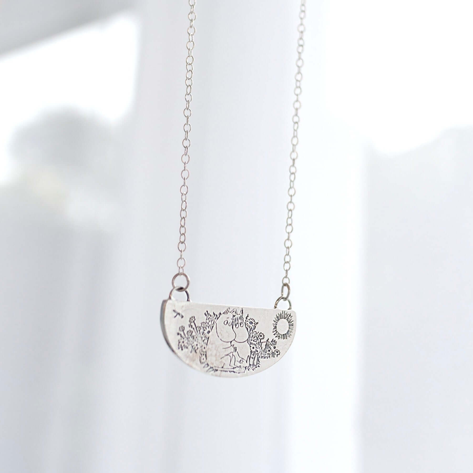 Sterling silver Moomin Friends Among Flowers Necklace hanging in natural light