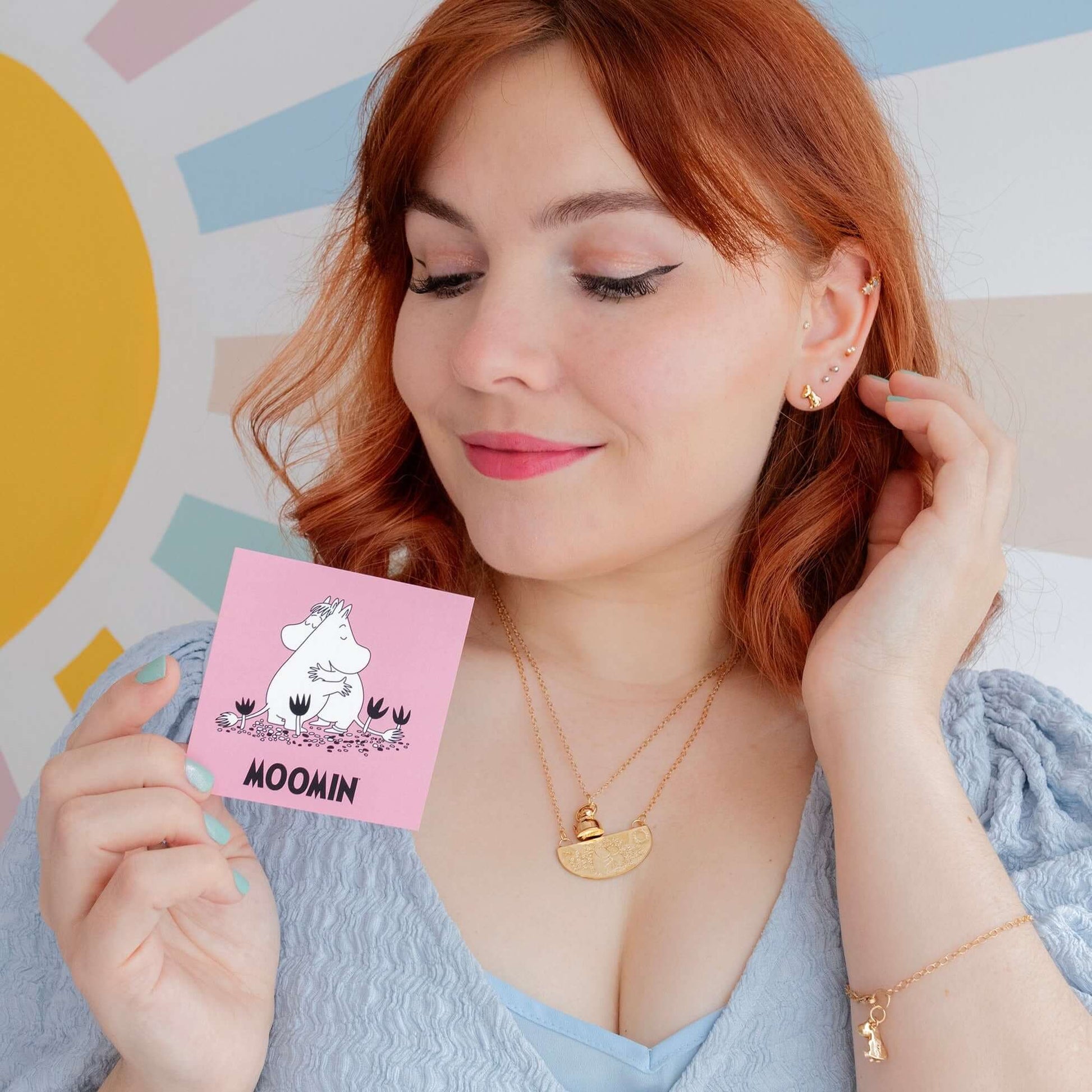 Model holding Licensed To Charm Moomin Stud Earrings in 18ct gold vermeil with branded packaging