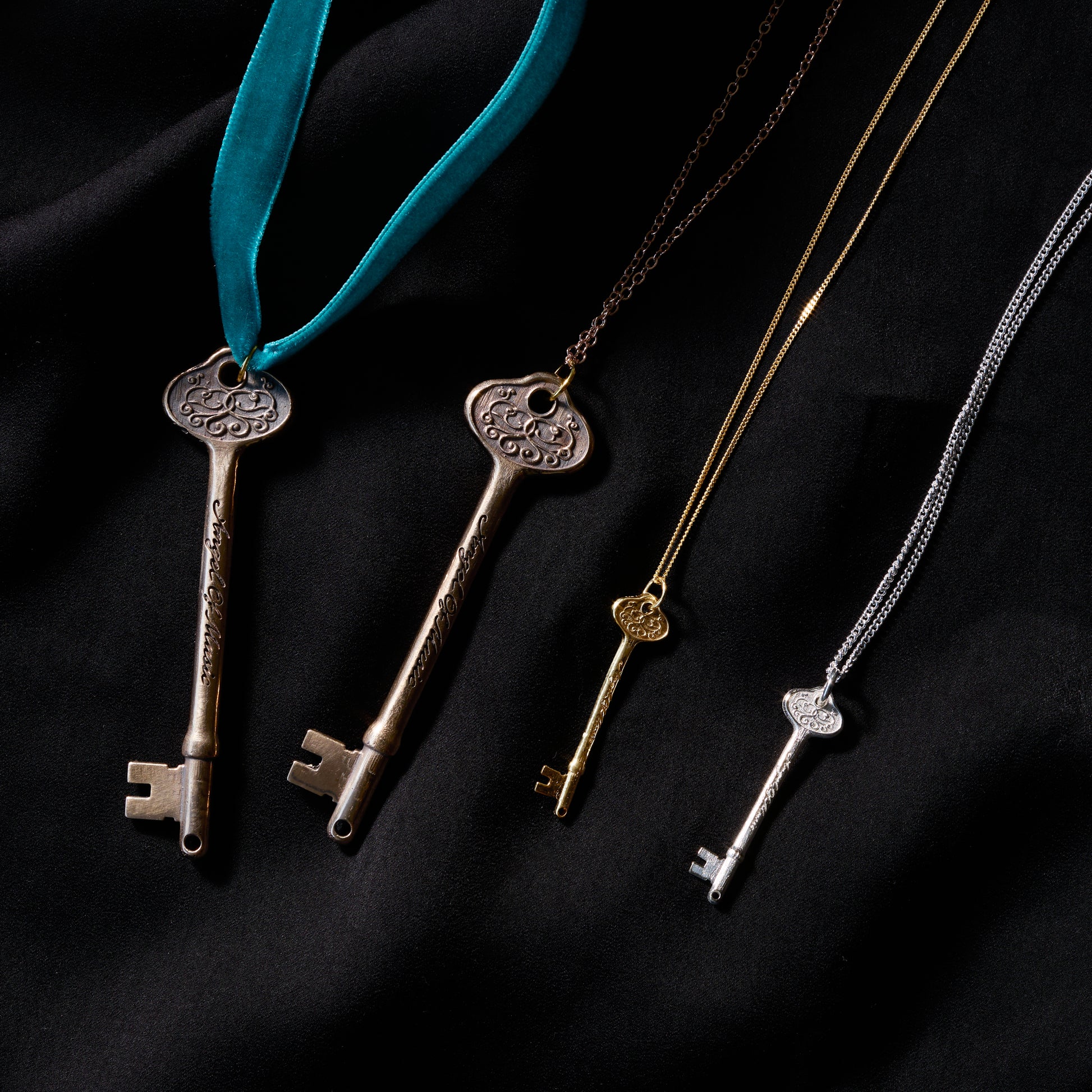 Licensed To Charm Phantom of the Opera key necklace collection in bronze, gold plated and sterling silver on black fabric background
