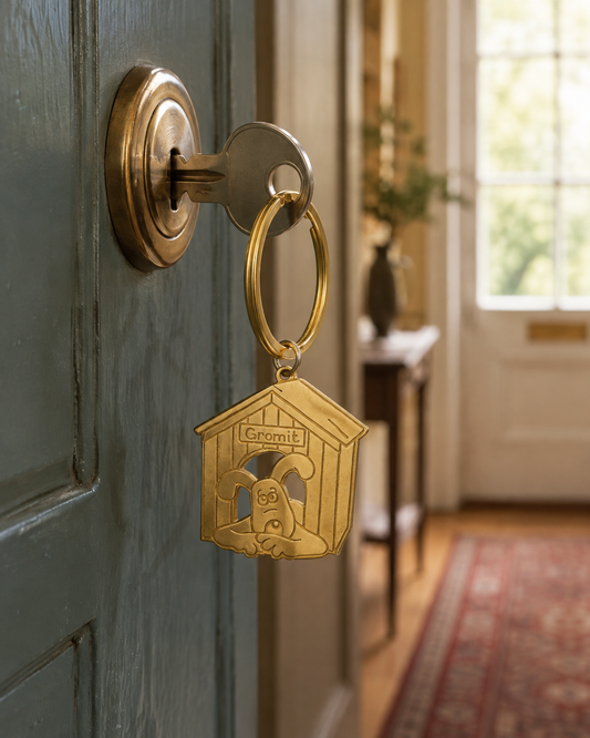 Licensed To Charm Wallace and Gromit Gromit doghouse keyring attached to a house key in a front door lock.