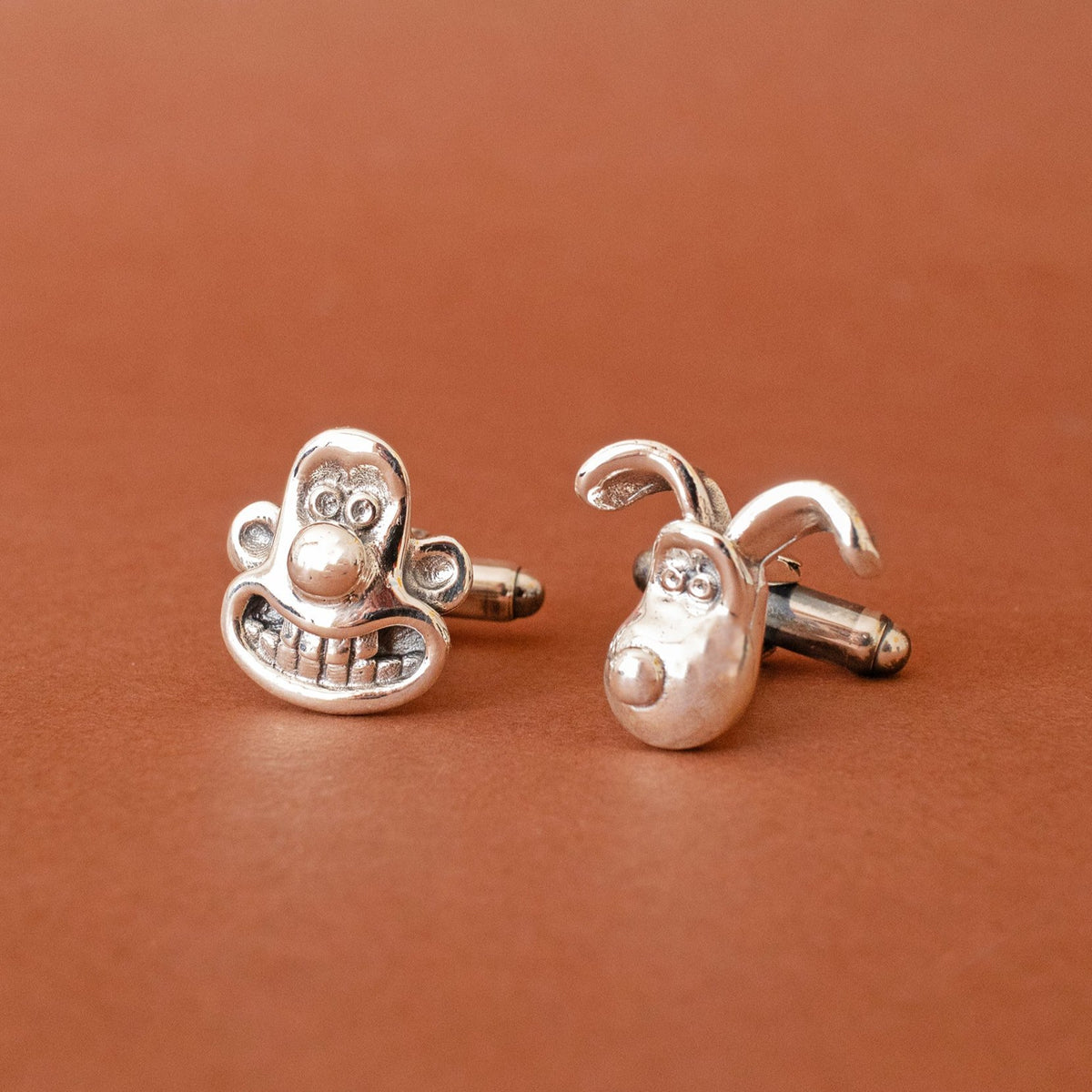 Licensed To Charm Wallace and Gromit recycled sterling silver cufflinks on a warm tan background