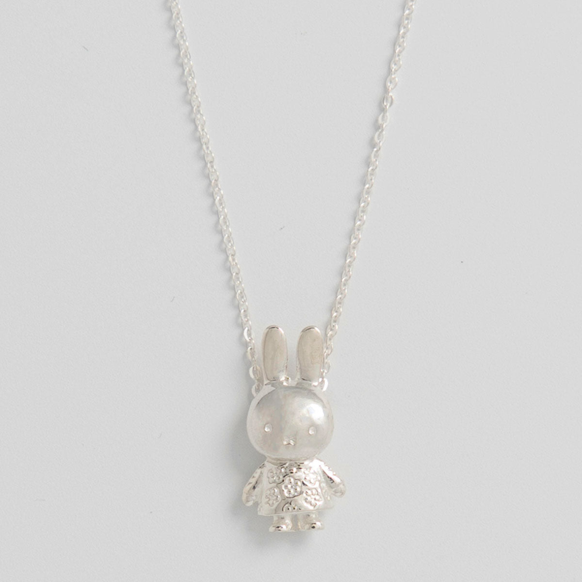 A close-up photograph of a silver Miffy pendant necklace featuring a 3D replica of Miffy's full body charm, hanging from a delicate silver chain