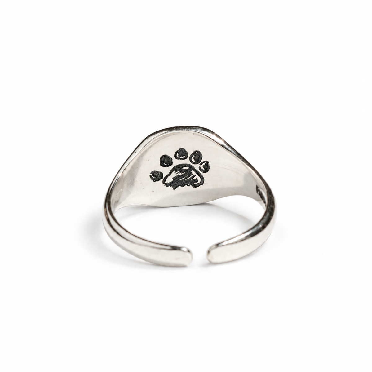 Close-up of the Paddington sterling silver adjustable signet ring featuring a hidden paw print engraving.