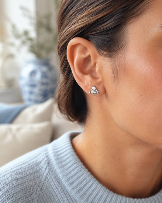 Close-up of a woman wearing small silver Paddington stud earrings with pale blue knitwear.