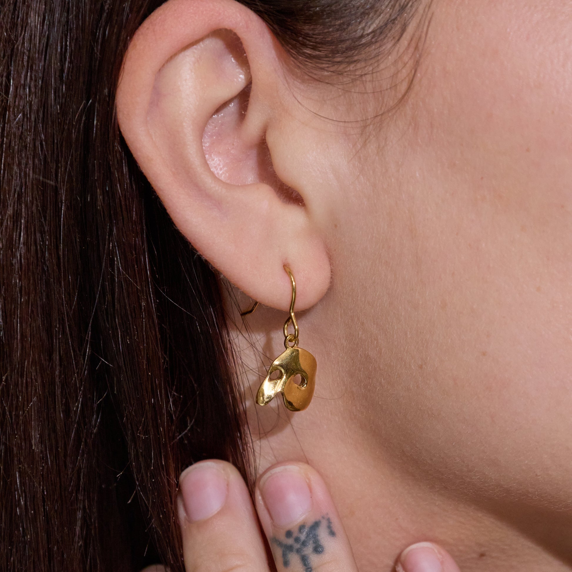 Licensed To Charm Model wearing Phantom mask gold drop earrings, elegant everyday theatre-inspired look