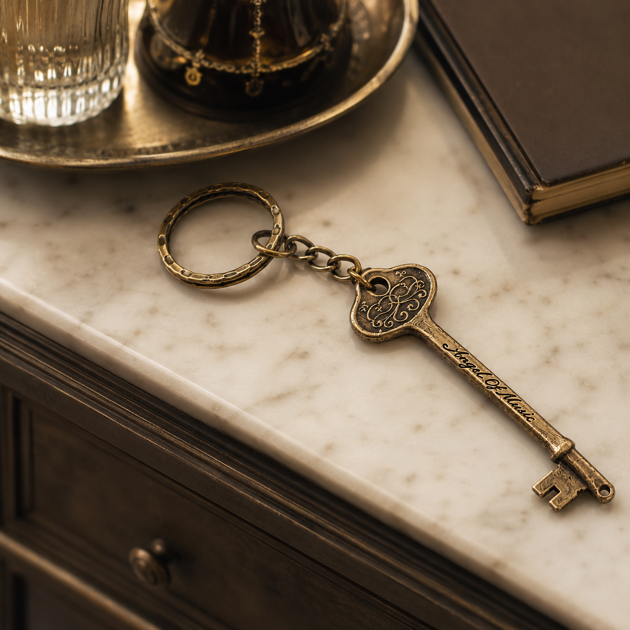 Phantom of the Opera bronze Angel of Music keyring displayed on an elegant marble entryway console.