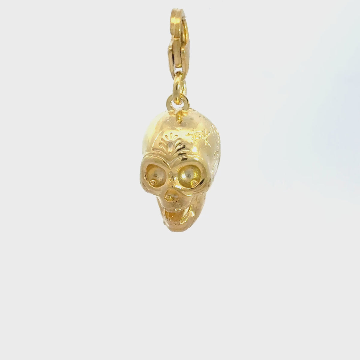 Close-up video of the Frida Kahlo Calavera skull clip-on charm in 18ct gold vermeil, showing decorative skull detailing and a lobster clasp.