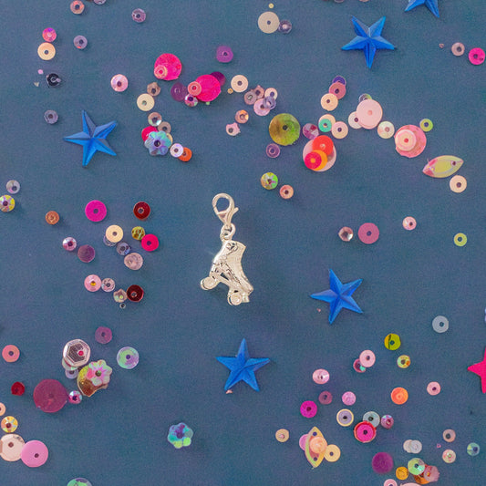 Official Starlight Express roller skate charm in sterling silver on blue background with colourful stars and sequins