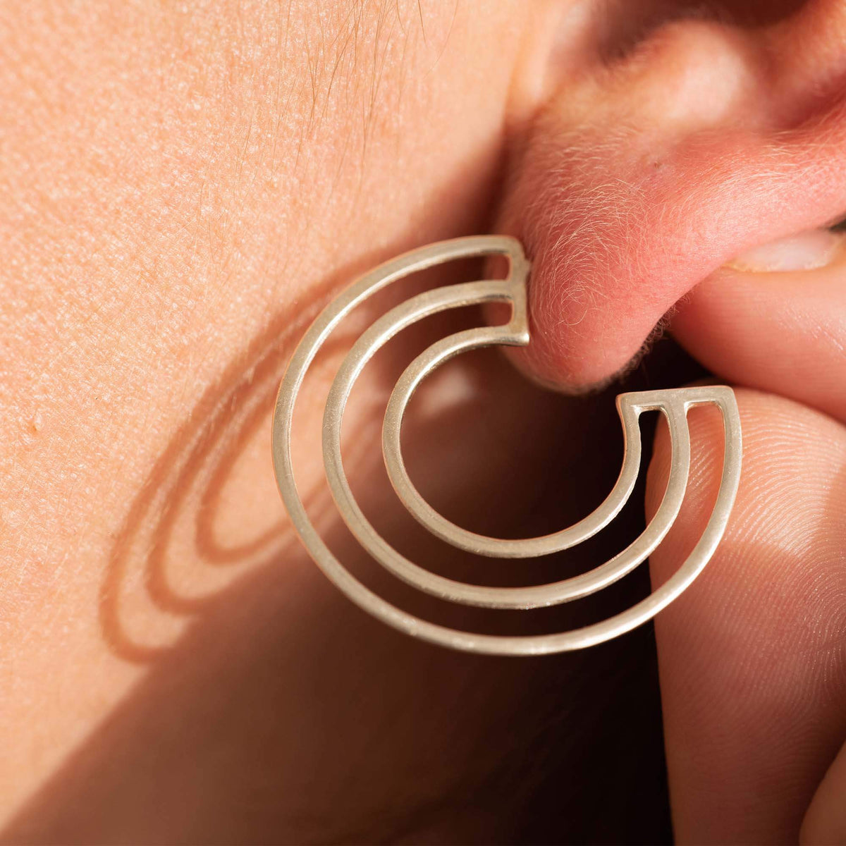Close-up of Licensed to Charm C Logo sterling silver hoop earrings