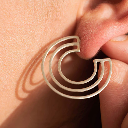 Close-up of Licensed to Charm C Logo sterling silver hoop earrings