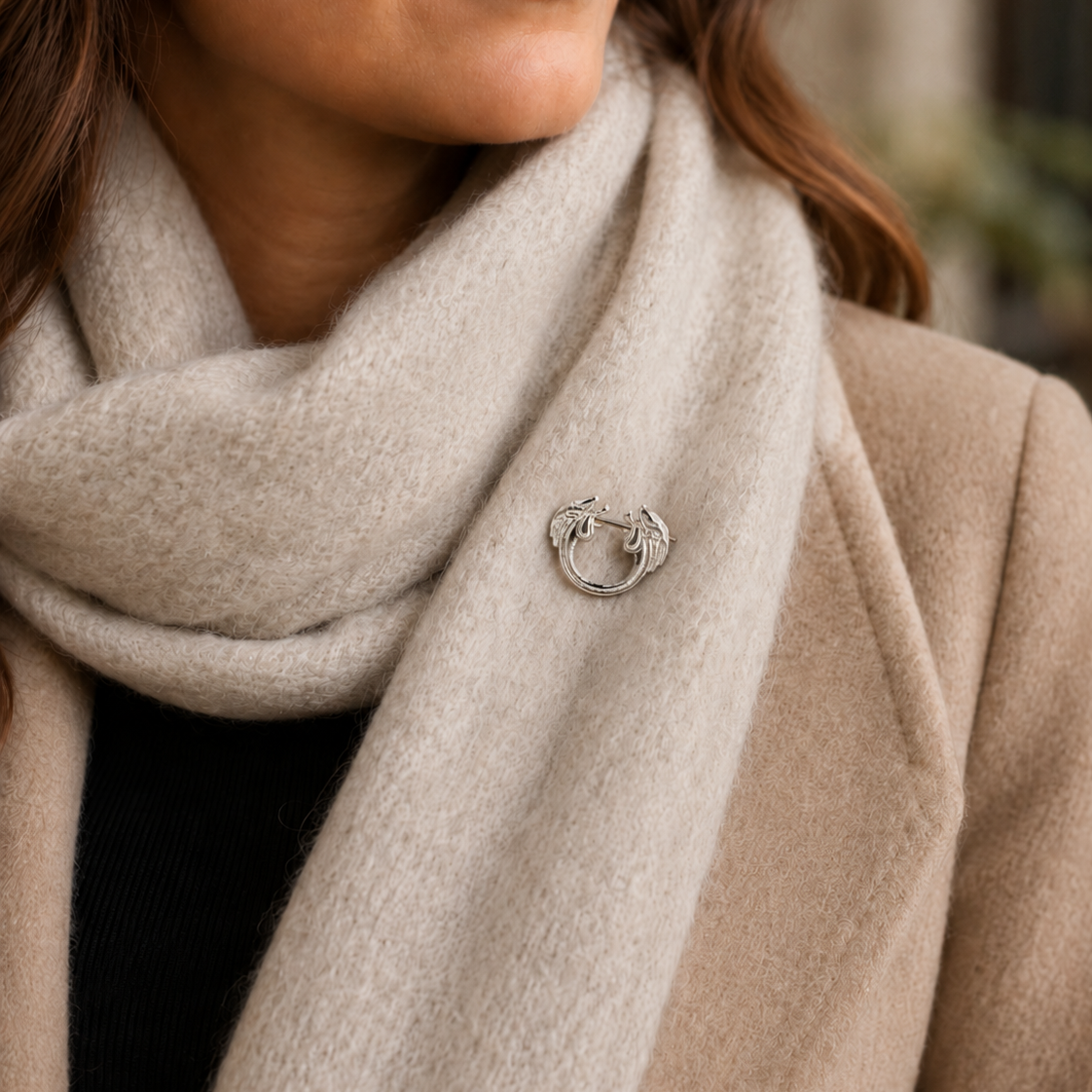 Sterling silver decorative pin brooch styled on a cream wool scarf with a camel coat