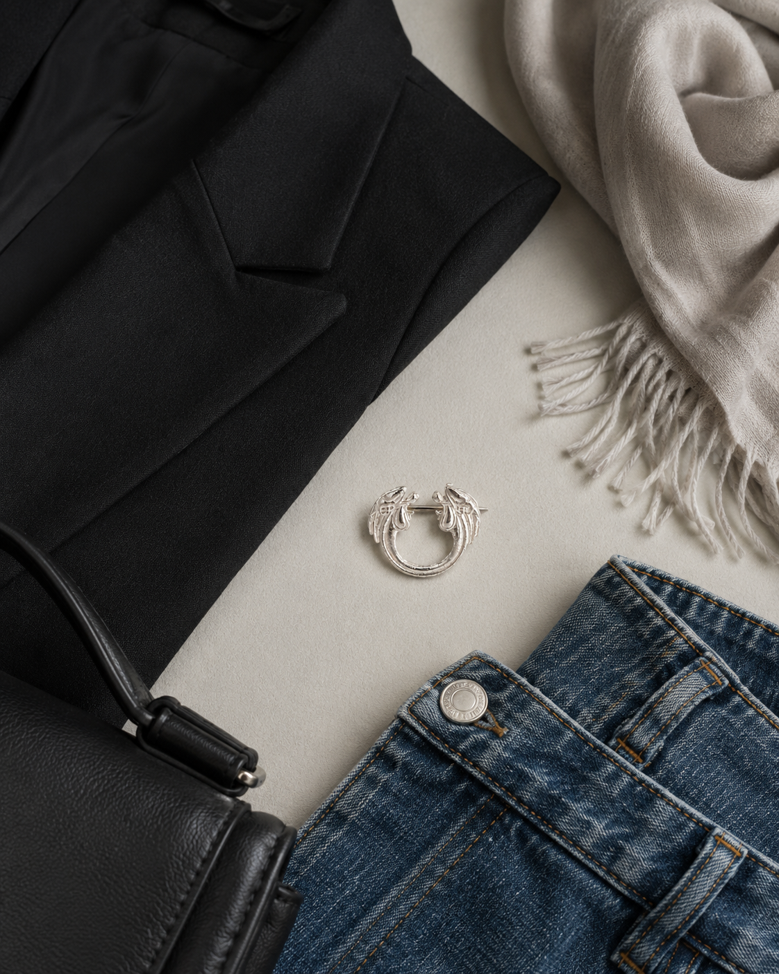 Sterling silver decorative pin brooch shown in a styling flat lay with blazer scarf denim jacket and bag