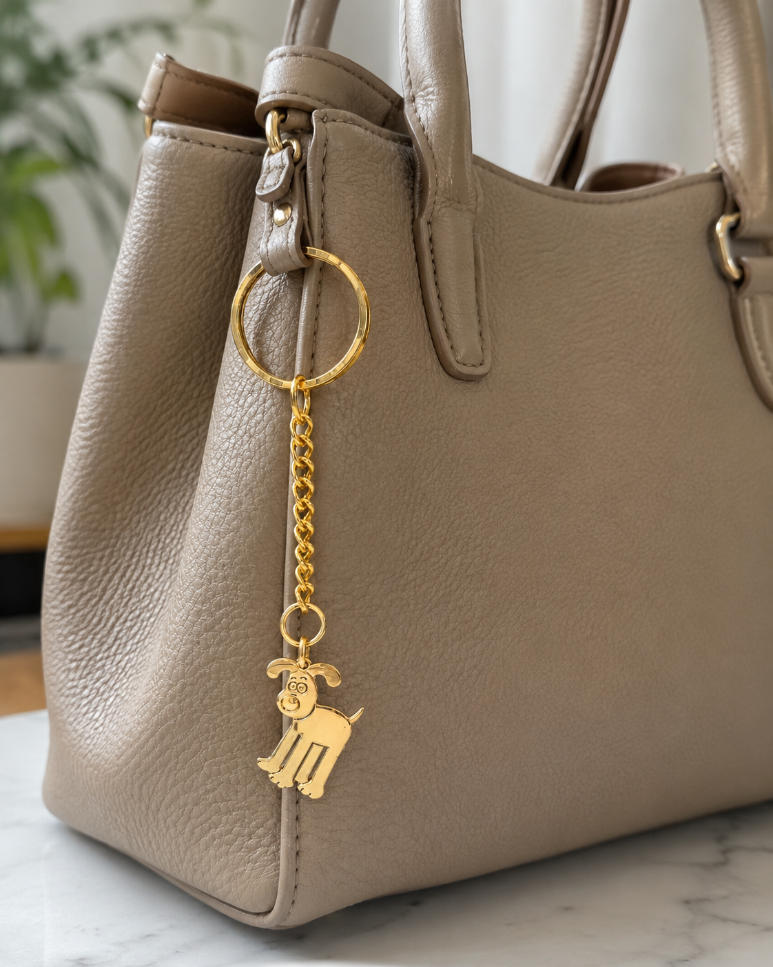 Gold Wallace & Gromit Gromit bag charm keyring attached to a green Wallace & Gromit backpack in a lifestyle setting