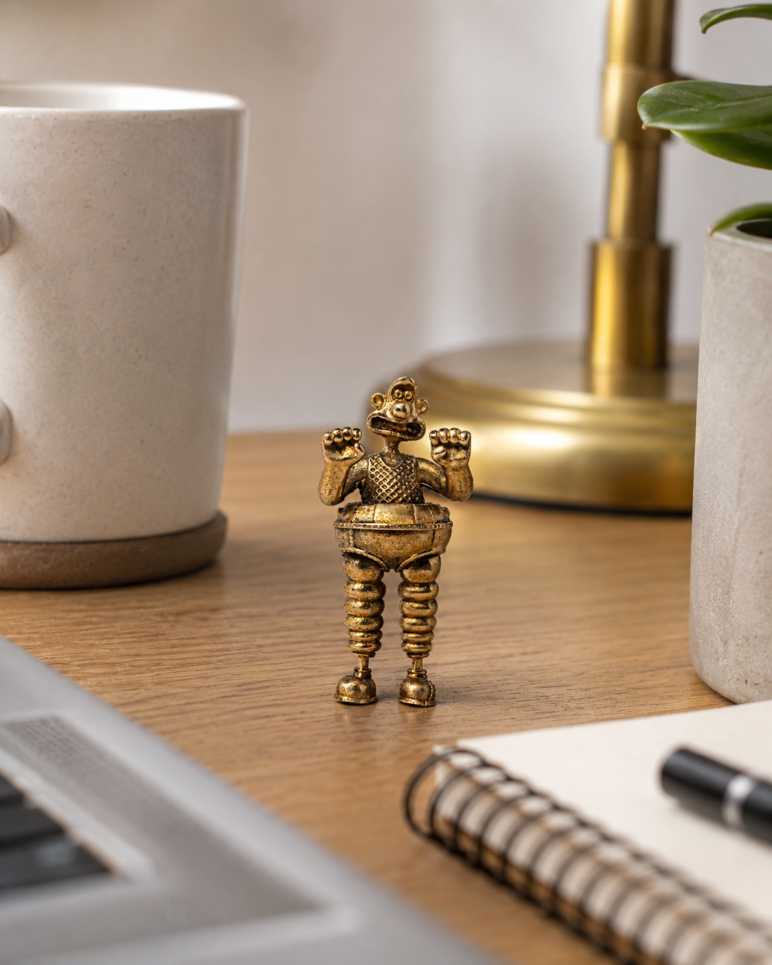 Small Wallace & Gromit Wrong Trousers bronze figurine styled on a desk beside a notebook, pen, plant and lamp