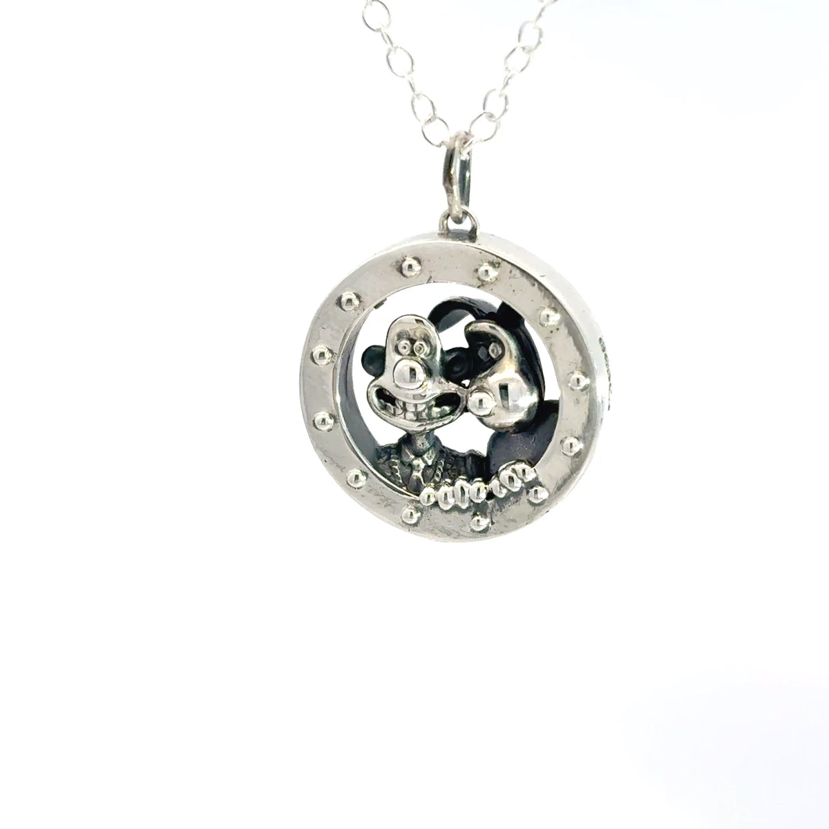 Close-up of the sterling silver rocket porthole pendant with Wallace and Gromit peering through the circular window, inspired by A Grand Day Out.