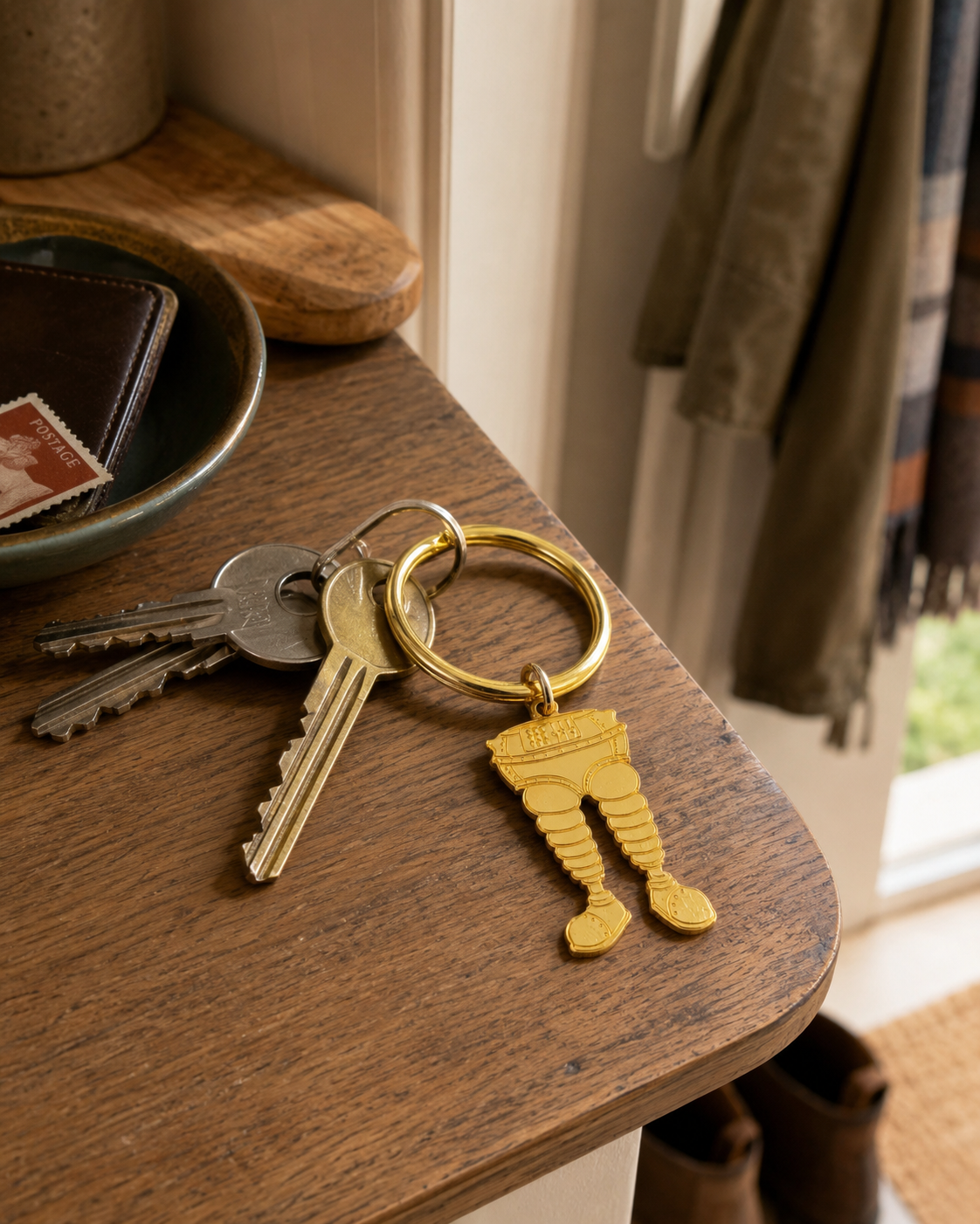 Wallace & Gromit Wrong Trousers gold keyring attached to house keys on a wooden hallway table.
